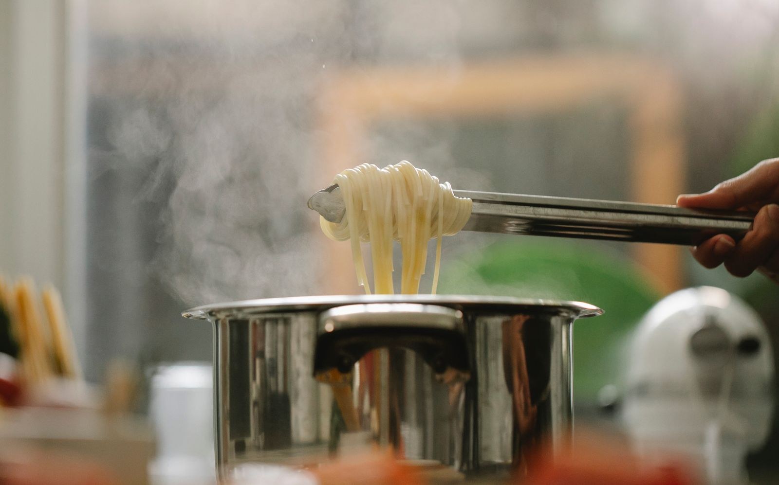 Lifting cooked pasta from the pot with tongs