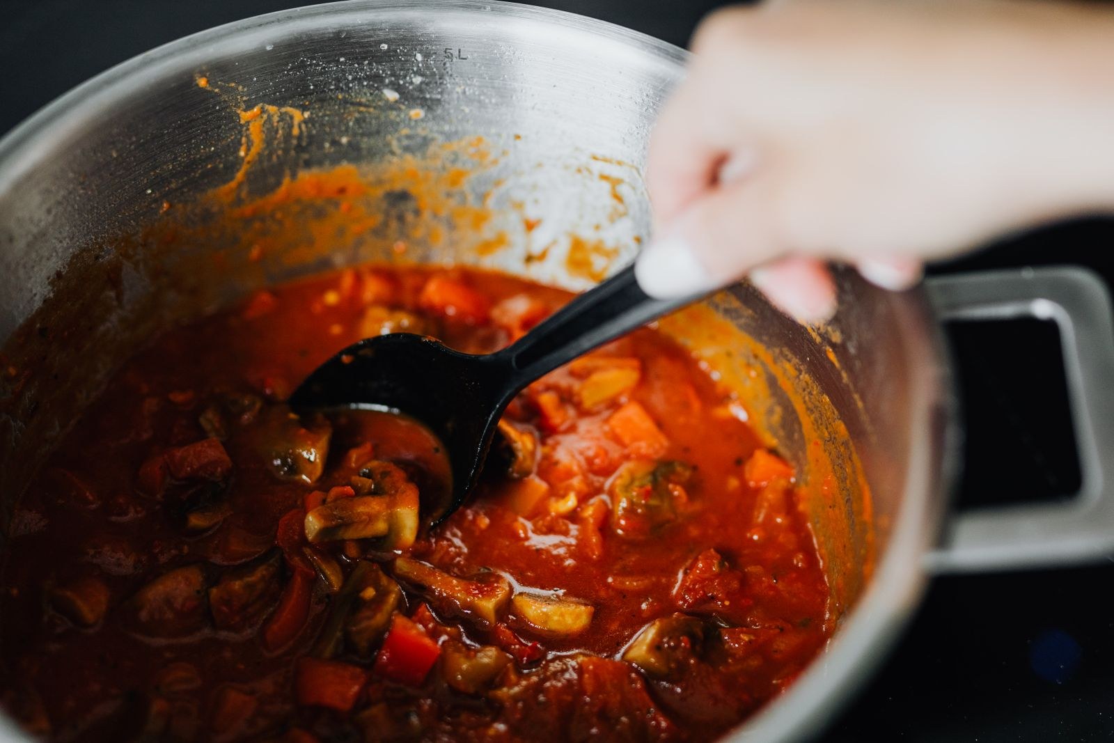 Stirring a thick gravy in a pot with a ladle