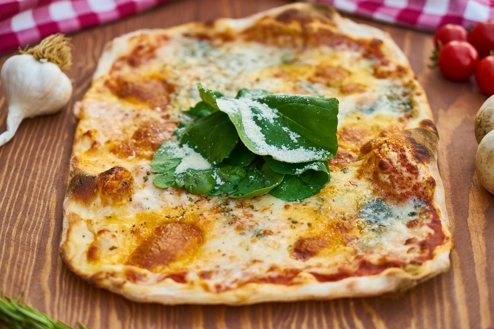 Thin crust topped with fresh arugula and bacon on a wooden table