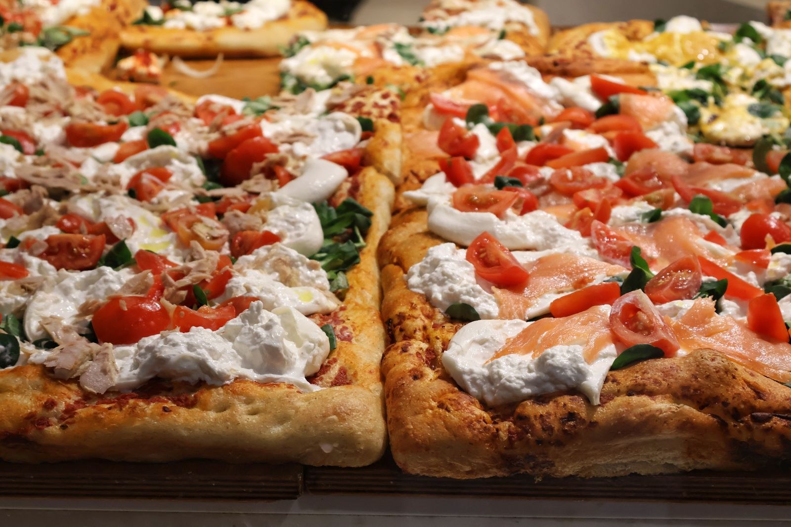 Pizza styles: rectangular Roman pizza al taglio slices with cured ham and greens