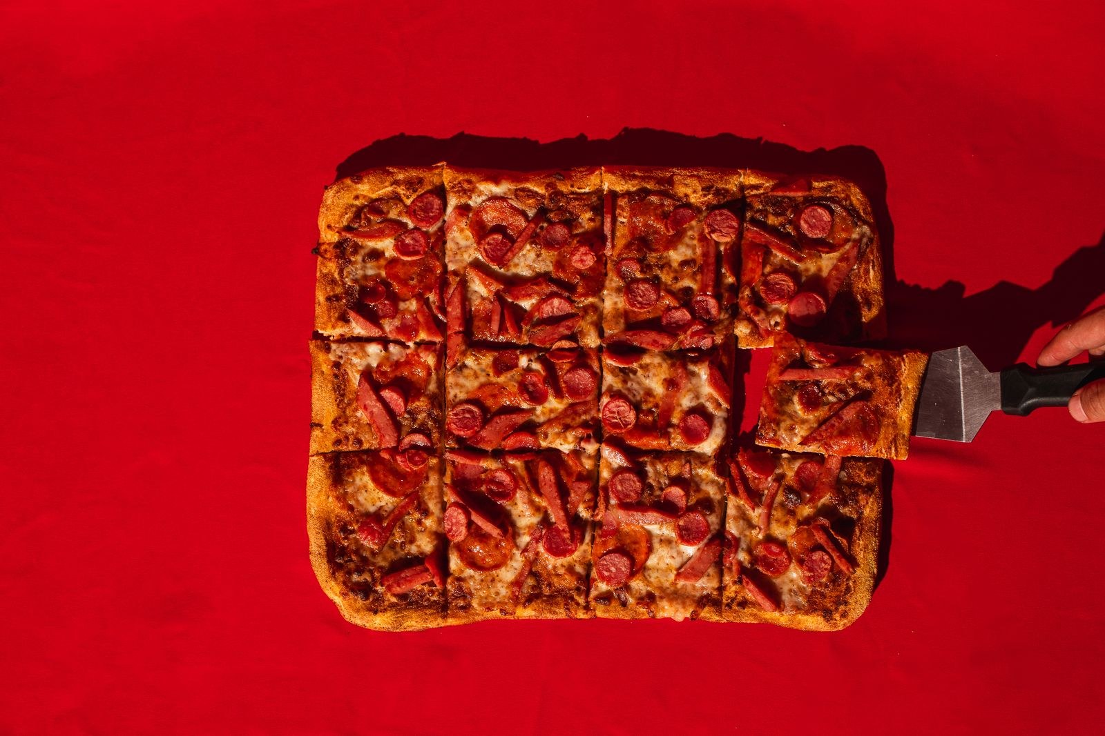 Pizza styles: thin square cut pizza with sausage like a St. Louis party cut