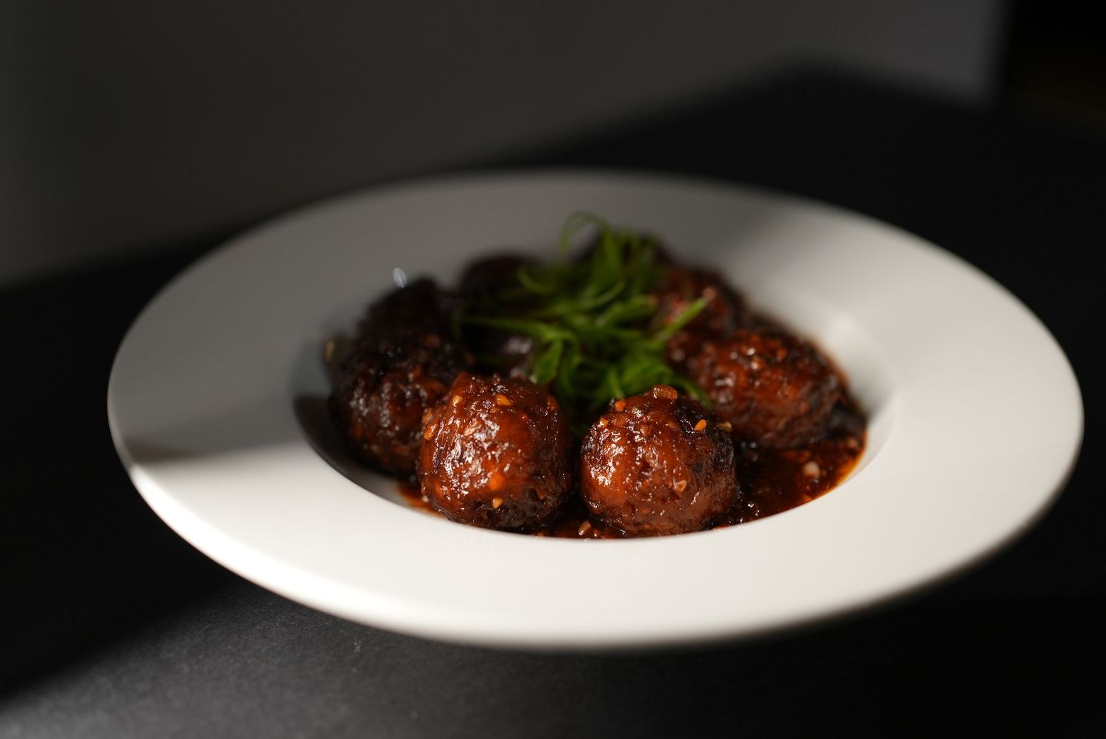Dark glazed meatballs on a white plate