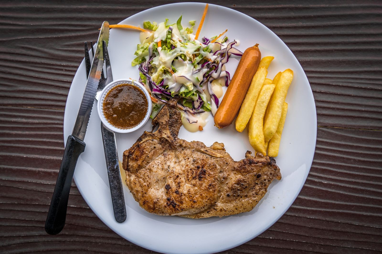 Apple cider dinners: seared pork chop with coleslaw and fries on a white plate