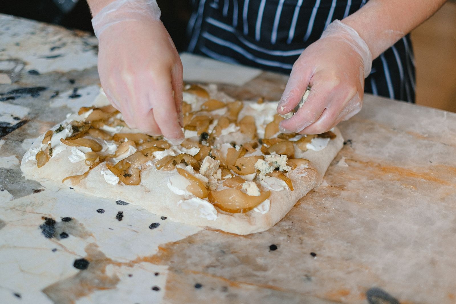 Focaccia recipes: hands pressing dimples and toppings into focaccia dough