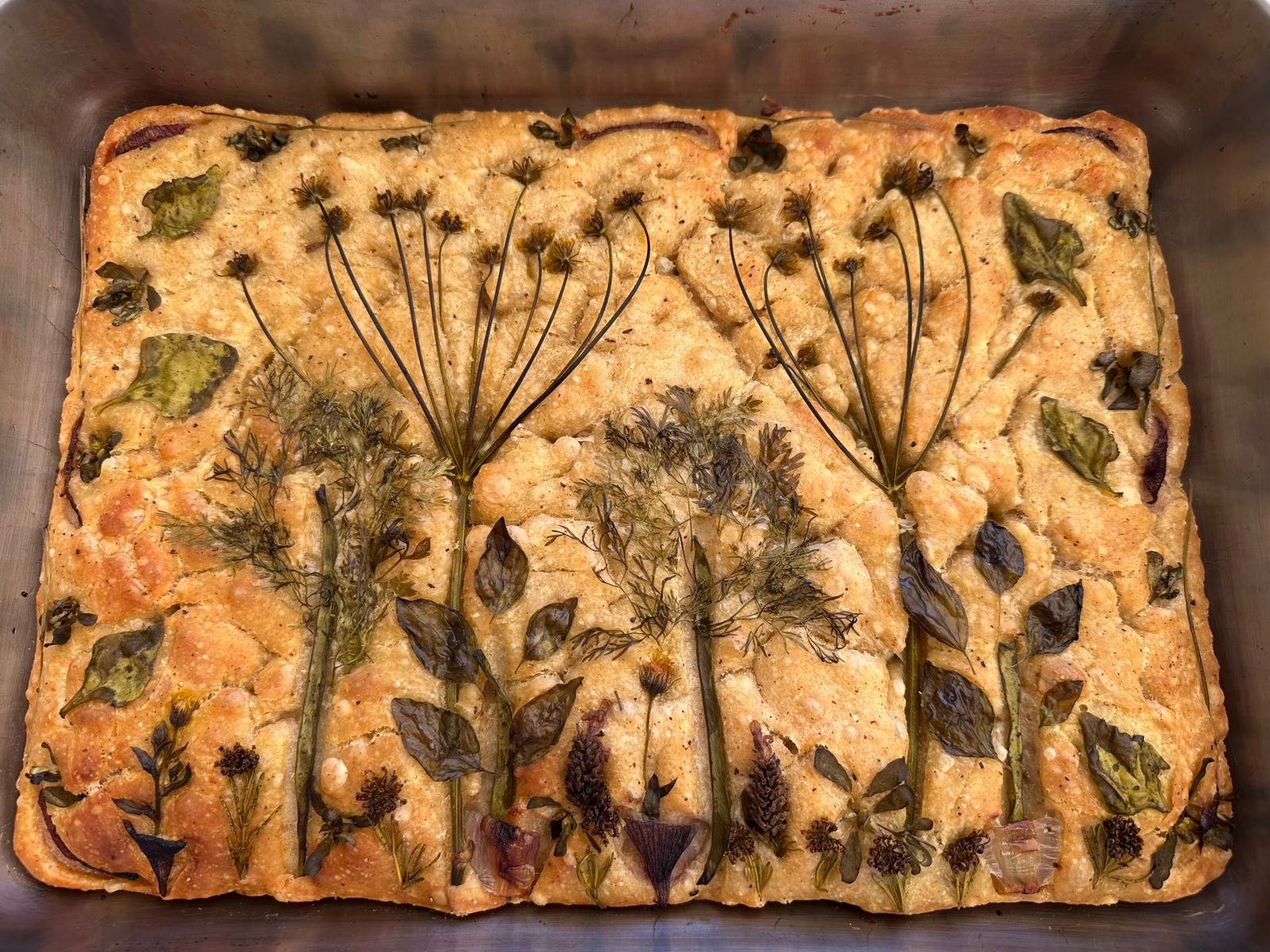 Herb flower art pressed into a golden baked loaf