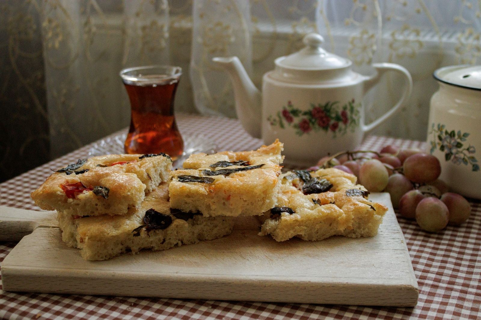 Homemade herb and olive loaf with tea and grapes