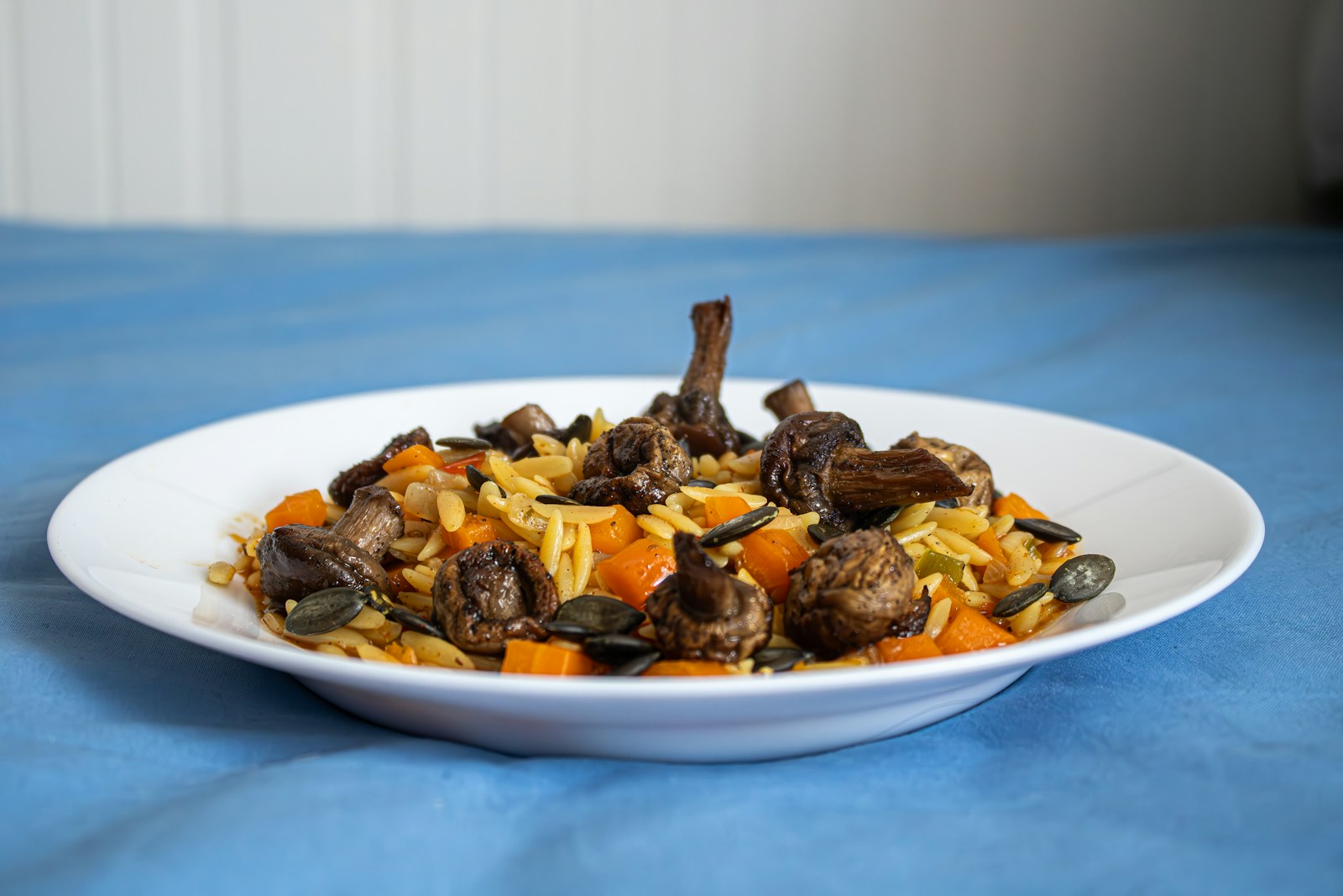 Orzo dinners: orzo pasta with roasted mushrooms and carrots on a white plate