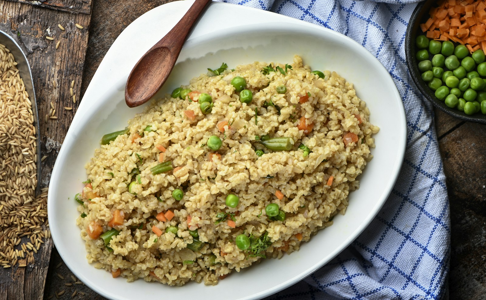 Golden orzo pilaf with peas and carrots in a white dish