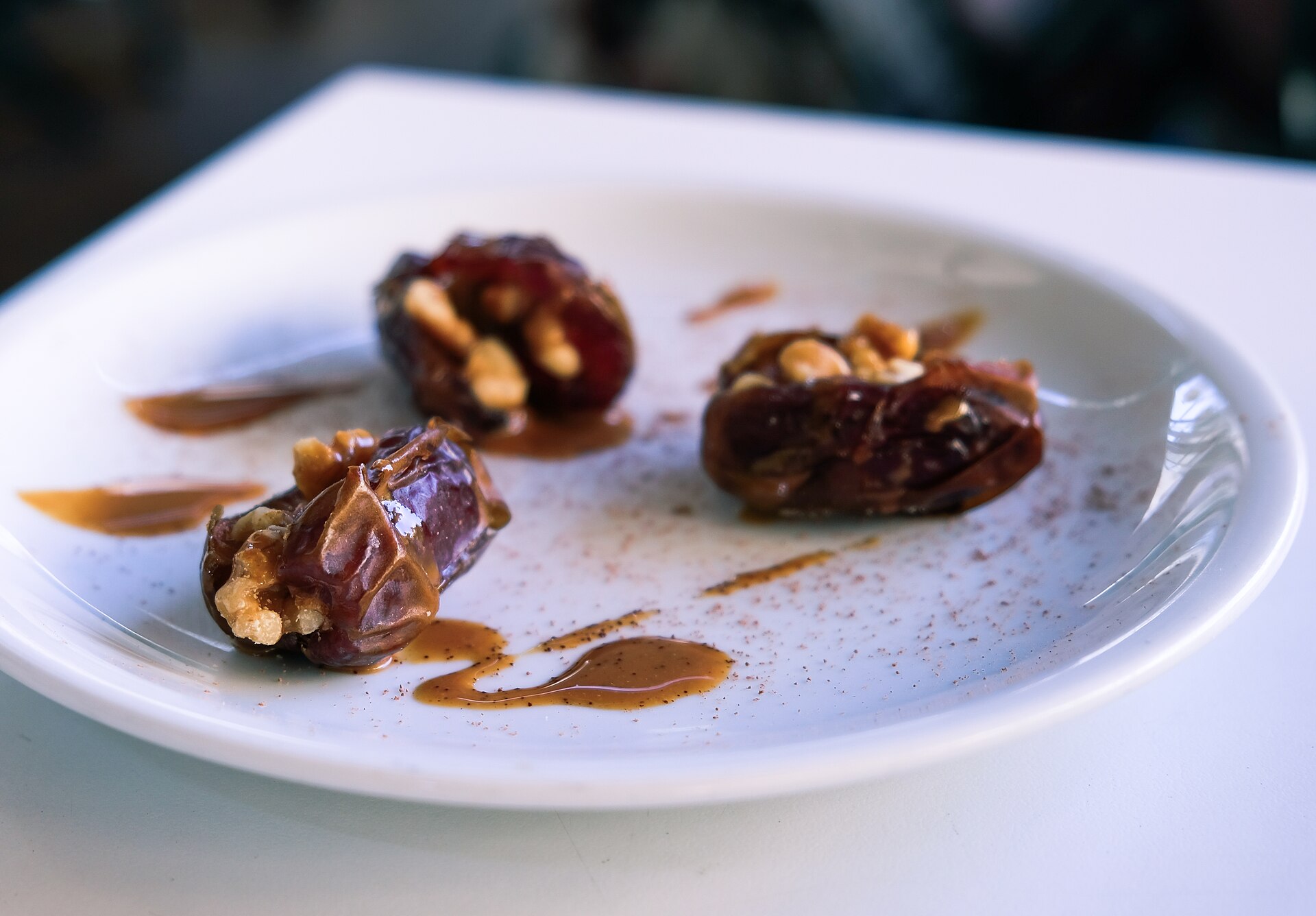 Stuffed dates with nuts and a caramel drizzle on a plate