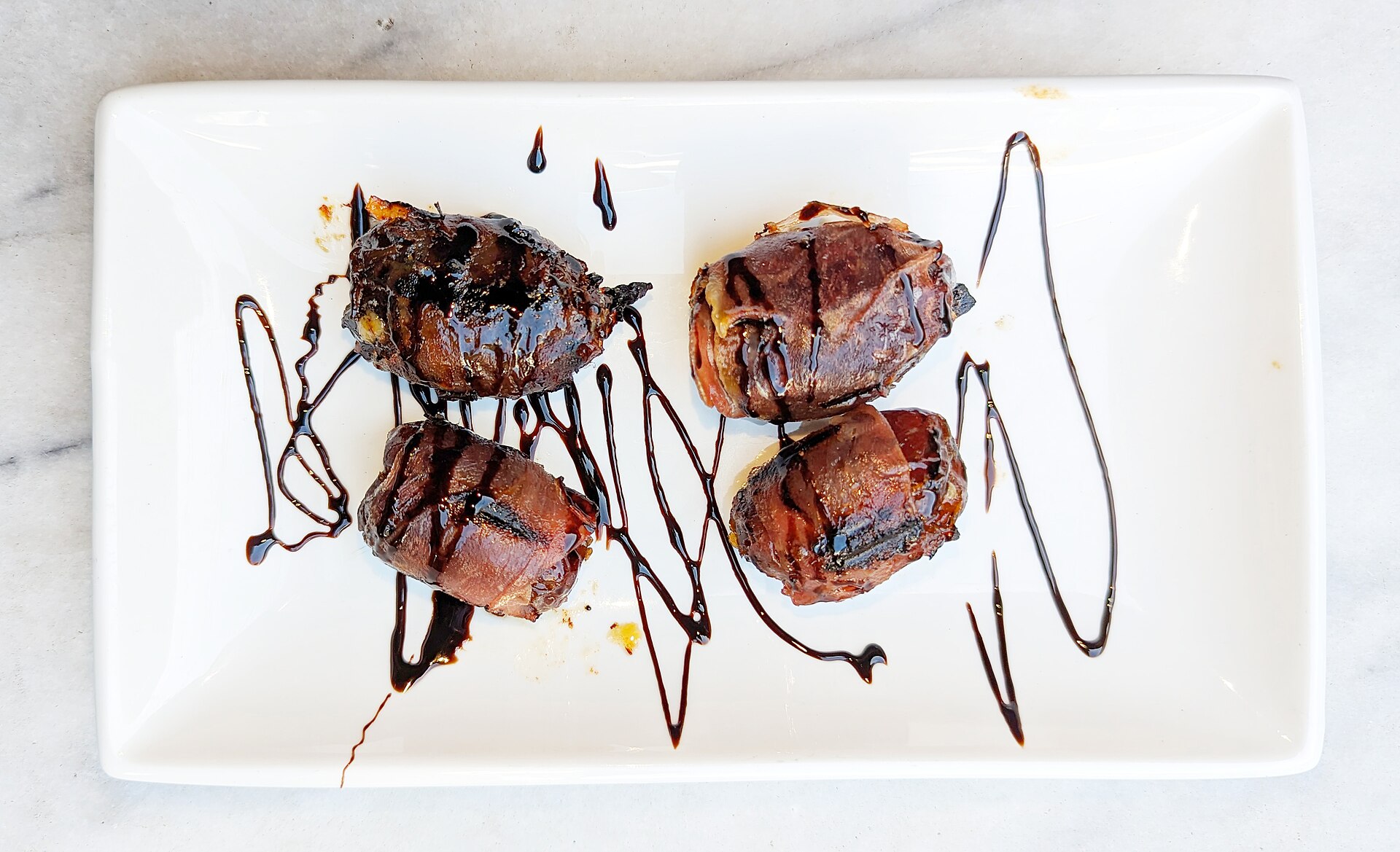 Stuffed dates wrapped in prosciutto with blue cheese on a plate