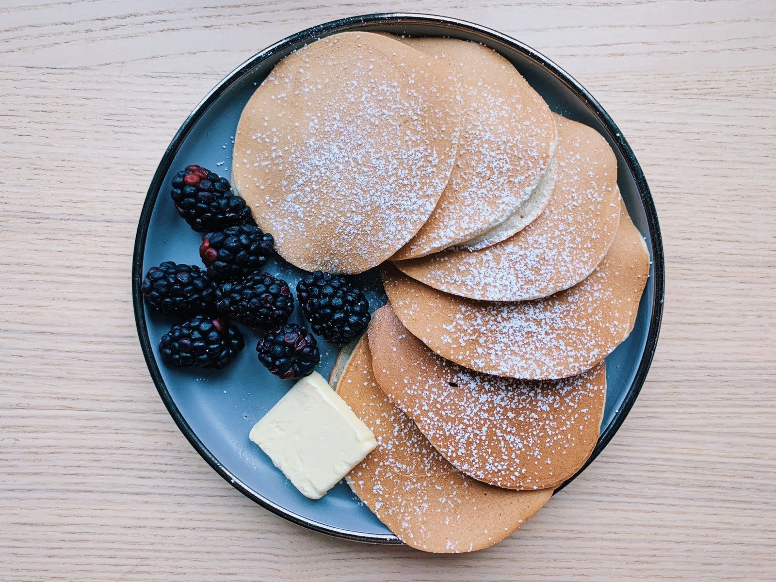 Pancakes with blackberries and butter on a wooden table