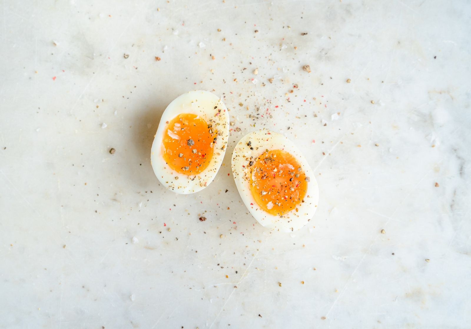 Two jammy halves with glossy orange yolks on marble