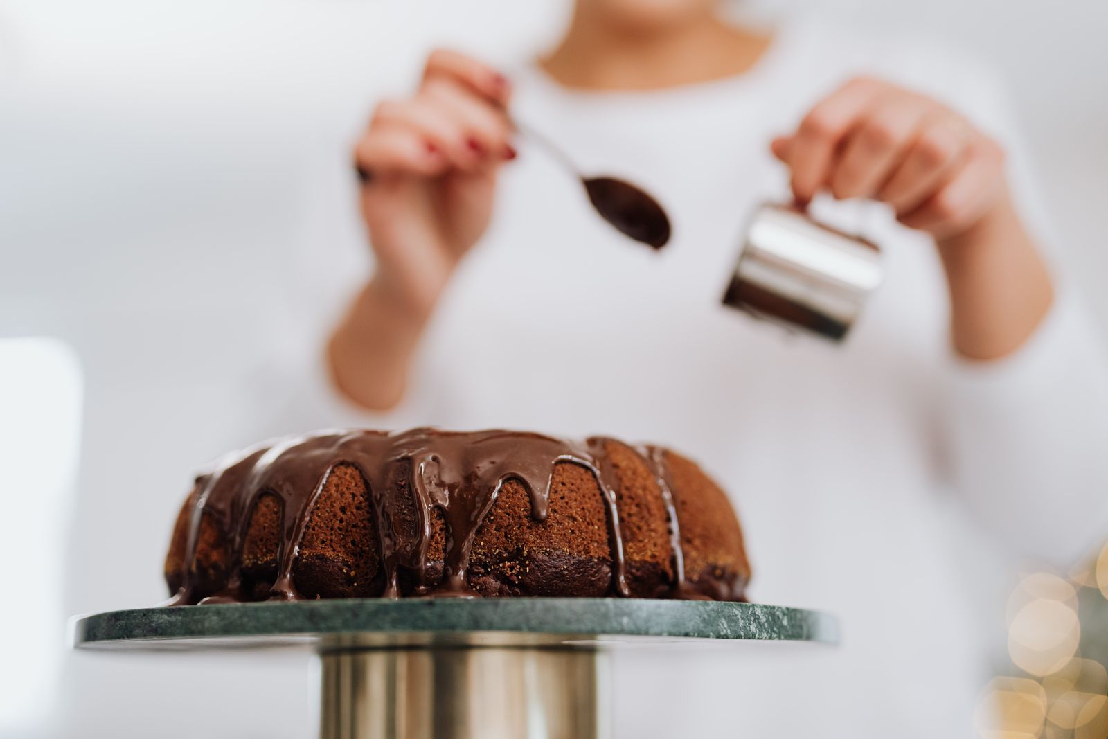 Ganache being poured over a ridged bundt on a stand
