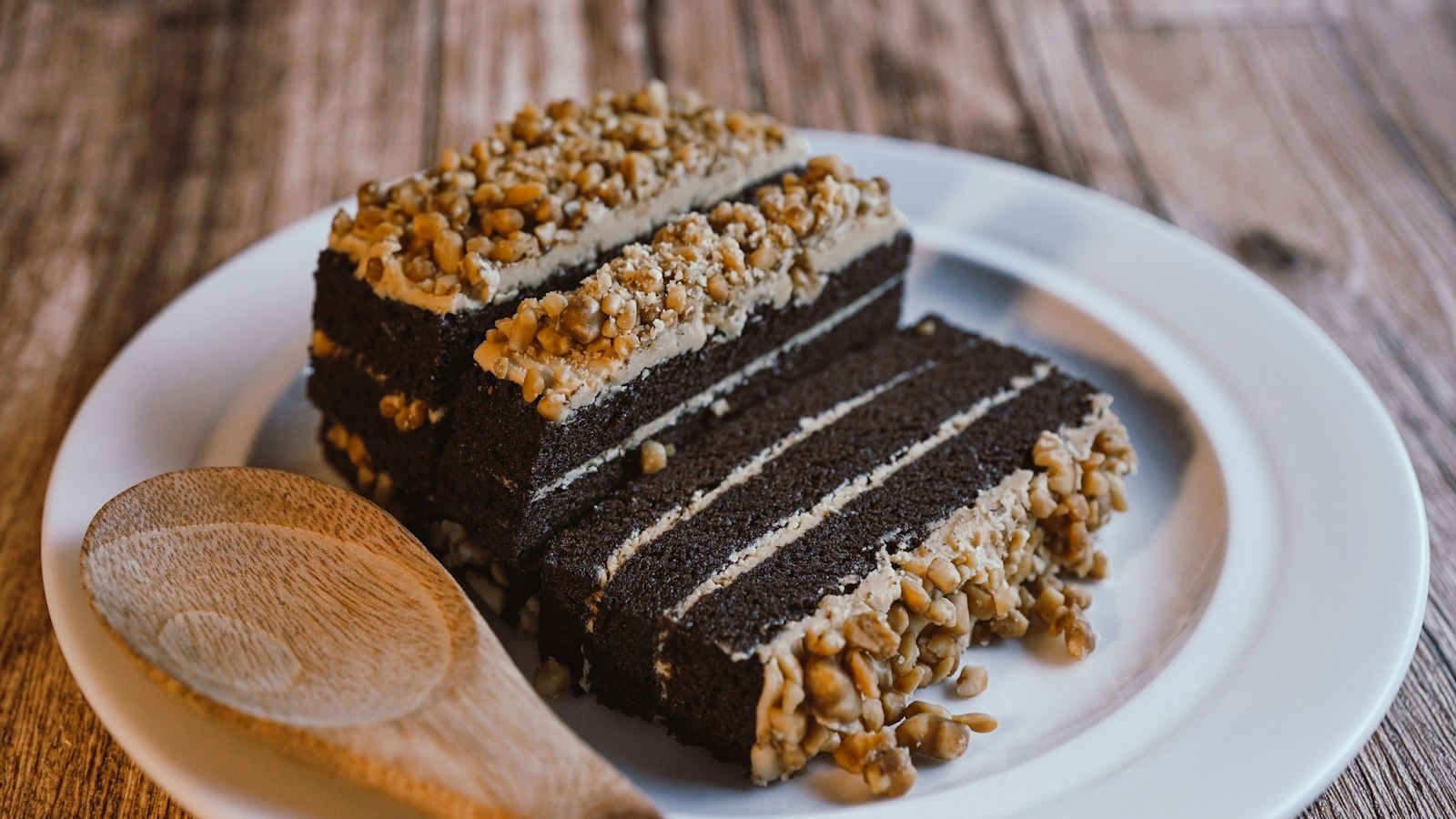 A layered slice with peanut butter frosting and a wooden spoon