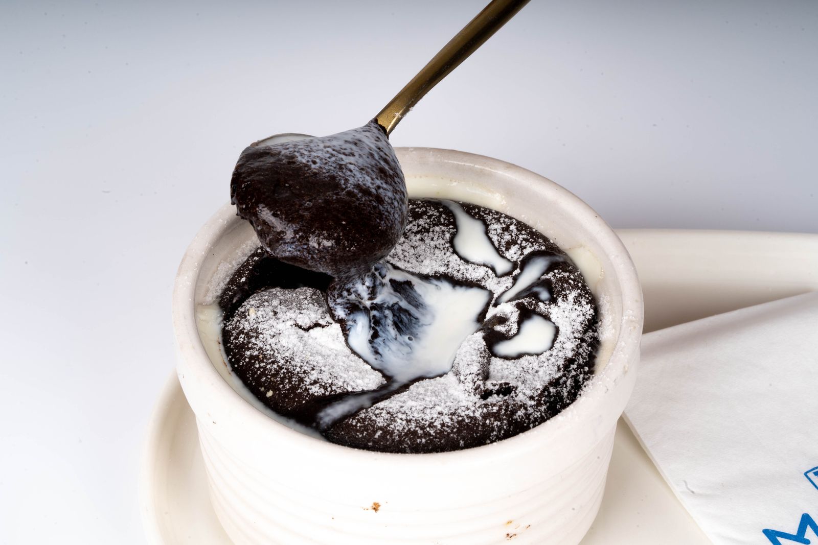 A spoon dipping into a warm cup of gooey fudge pudding