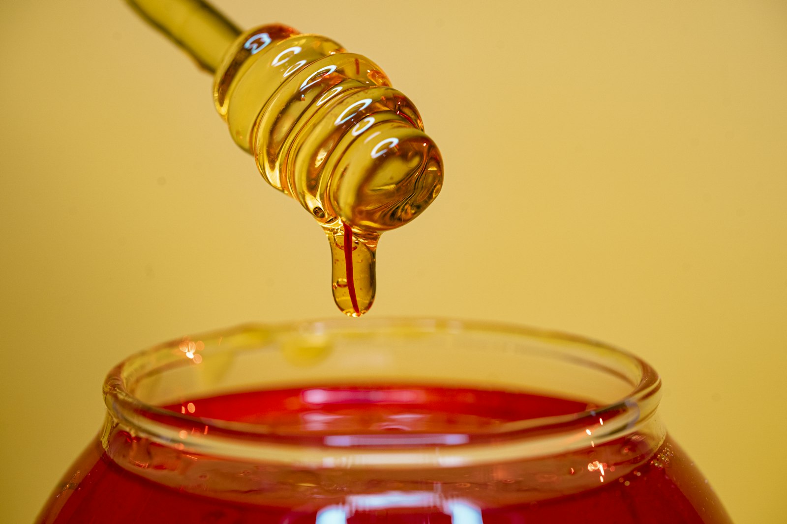 Honey dripping into a jar to make homemade hot honey