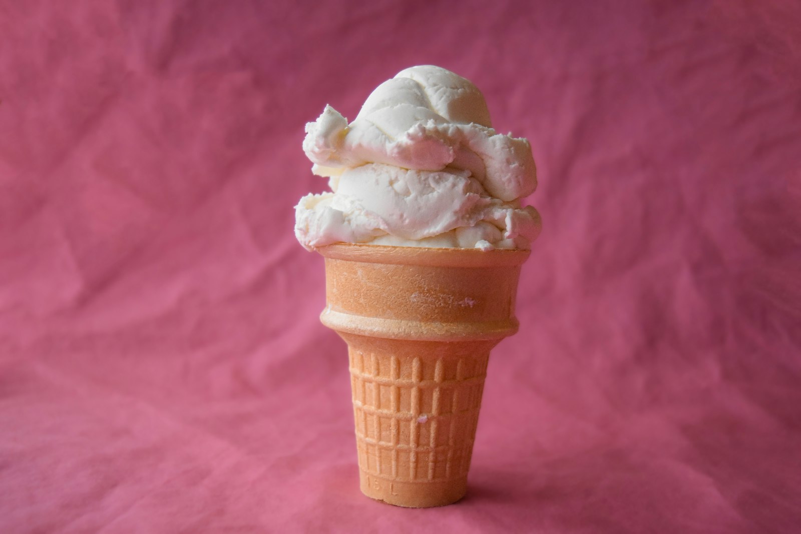 Vanilla ice cream cone on a pink background