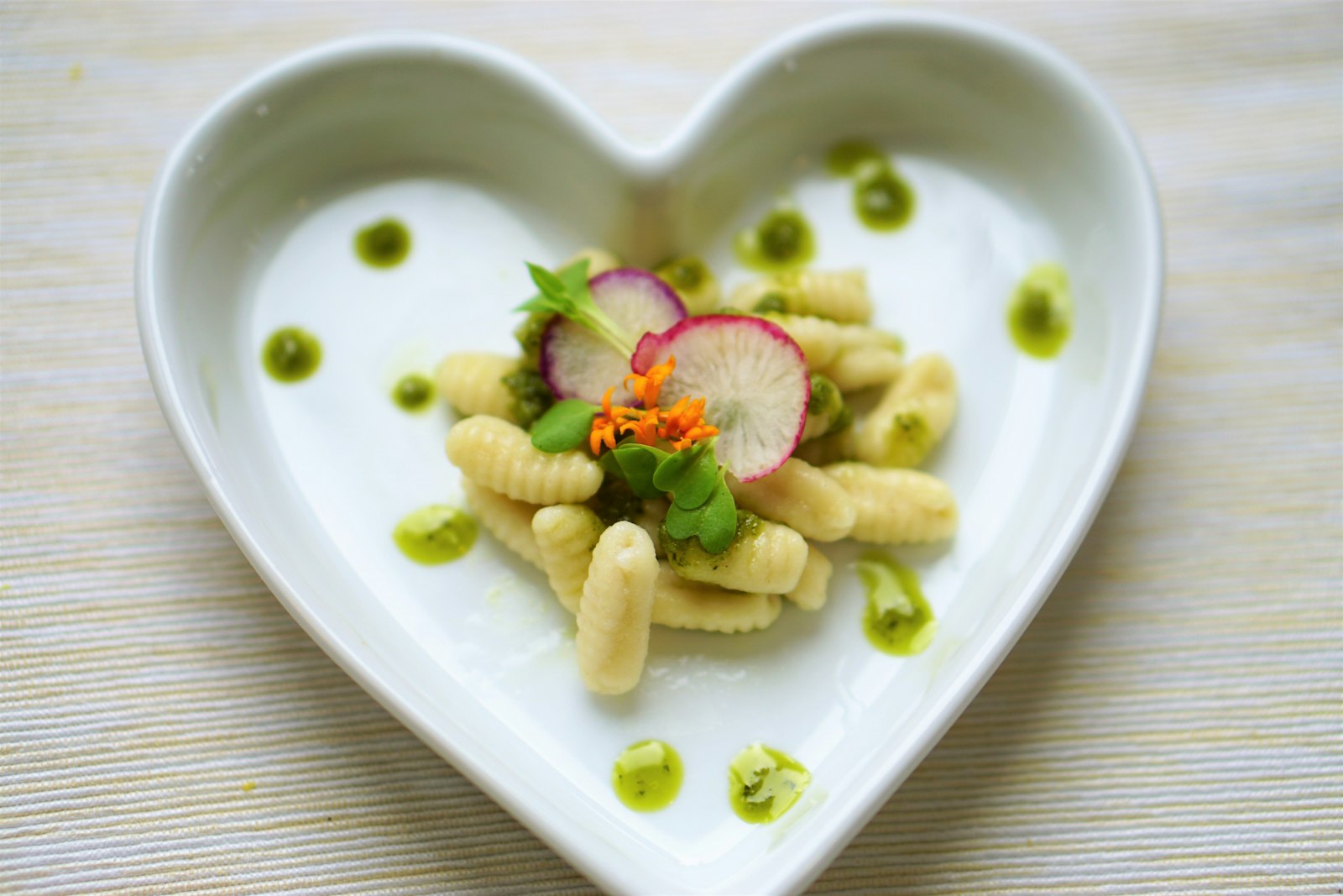 Pesto dumplings with radish and herbs in a heart shaped dish