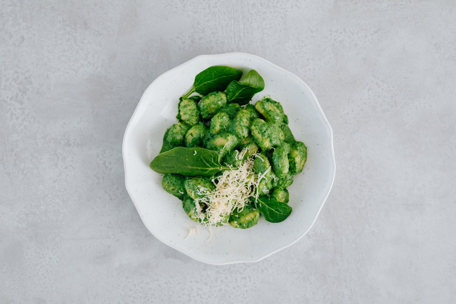 Gnocchi dinners: green spinach gnocchi with Parmesan on a white plate