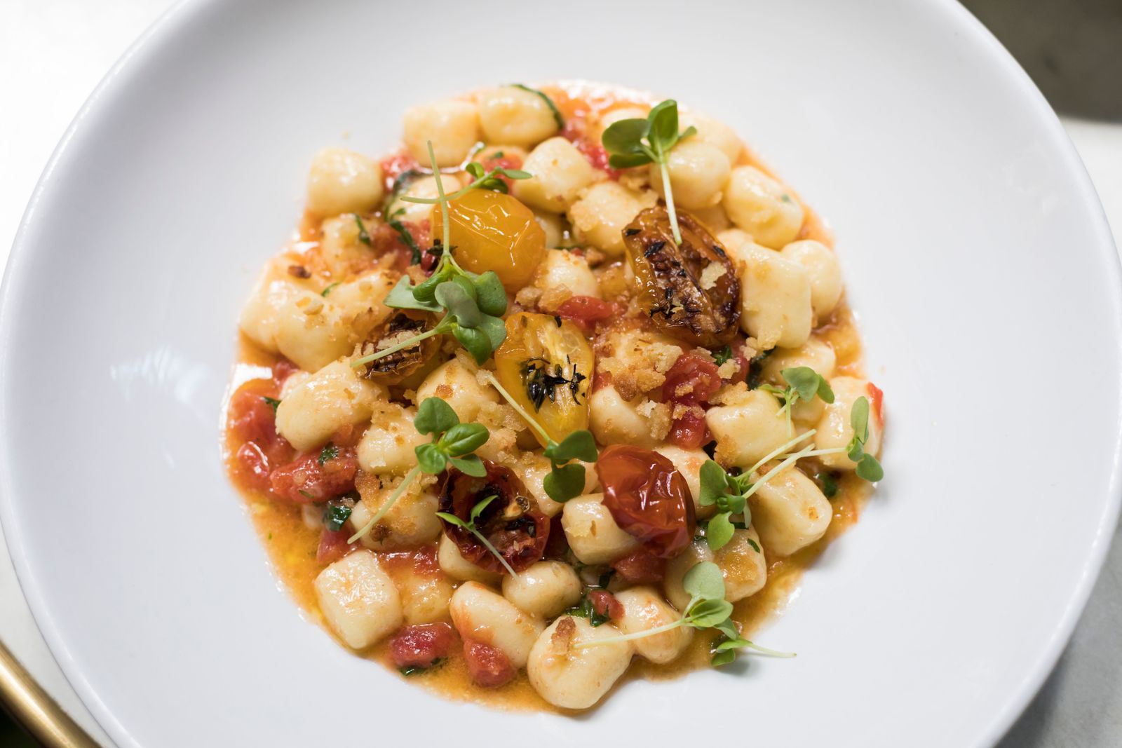 Fresh tomatoes and herbs over potato dumplings on a plate