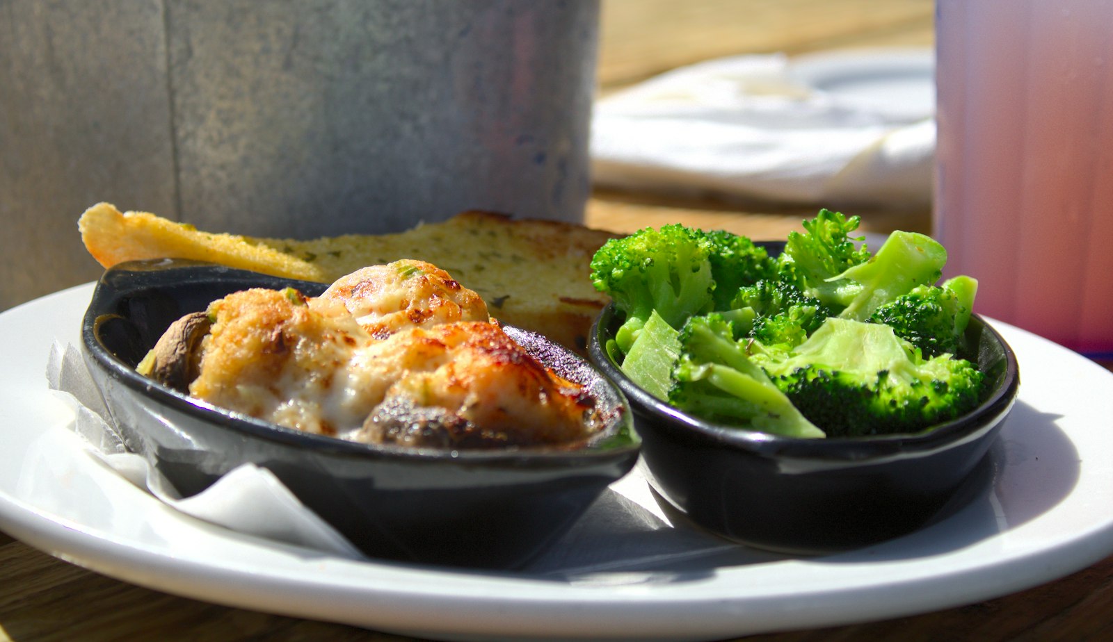 Cauliflower cheese gratin in a dark dish served next to broccoli
