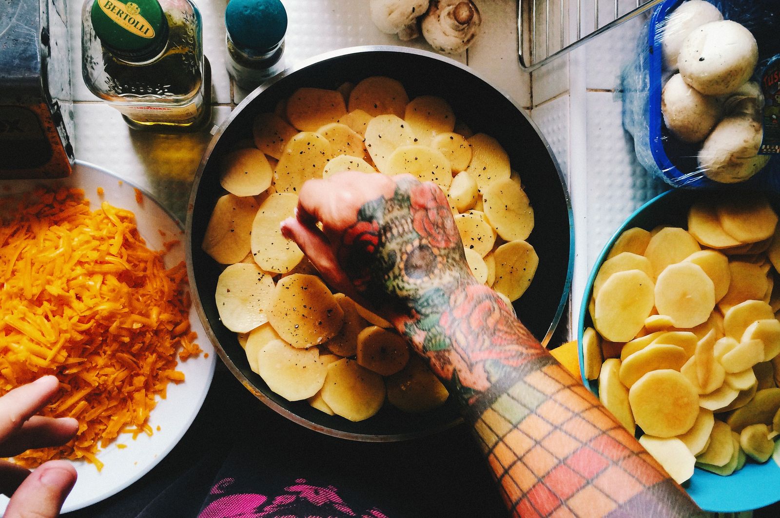 Hands arranging thin potato slices in a spiral in a pan
