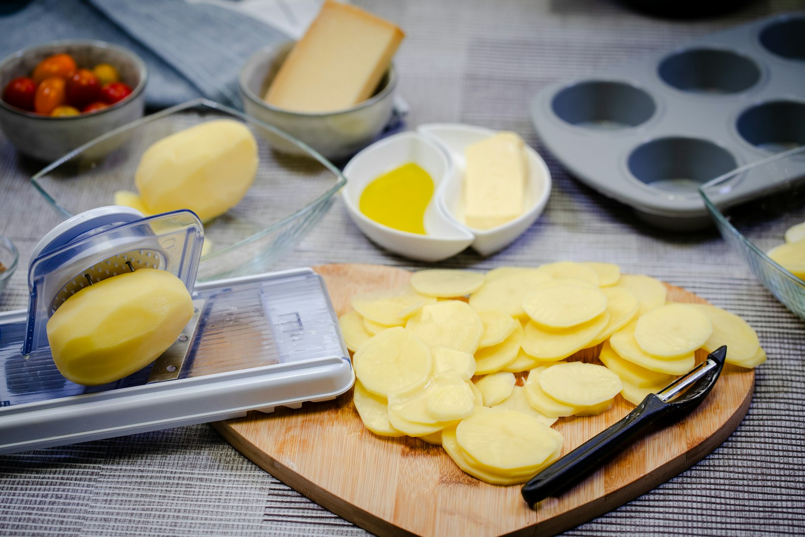 Potatoes sliced thin with a mandoline on a cutting board for a make-ahead gratin