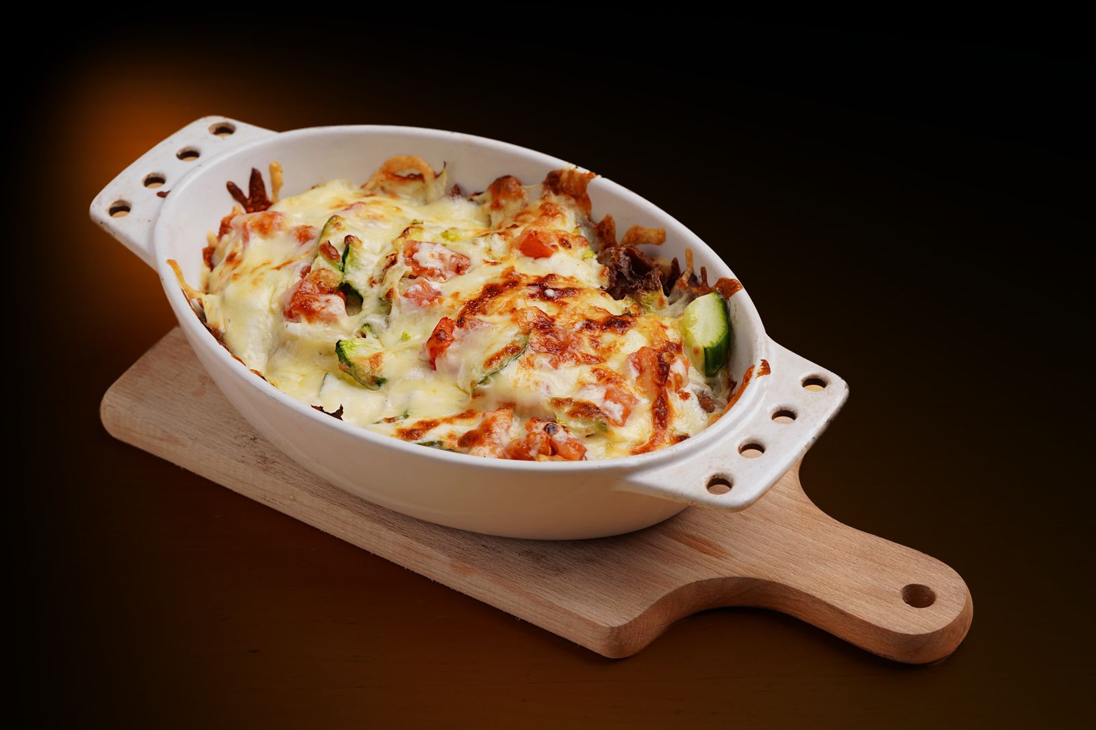 A cheesy mixed vegetable gratin in a white oval dish