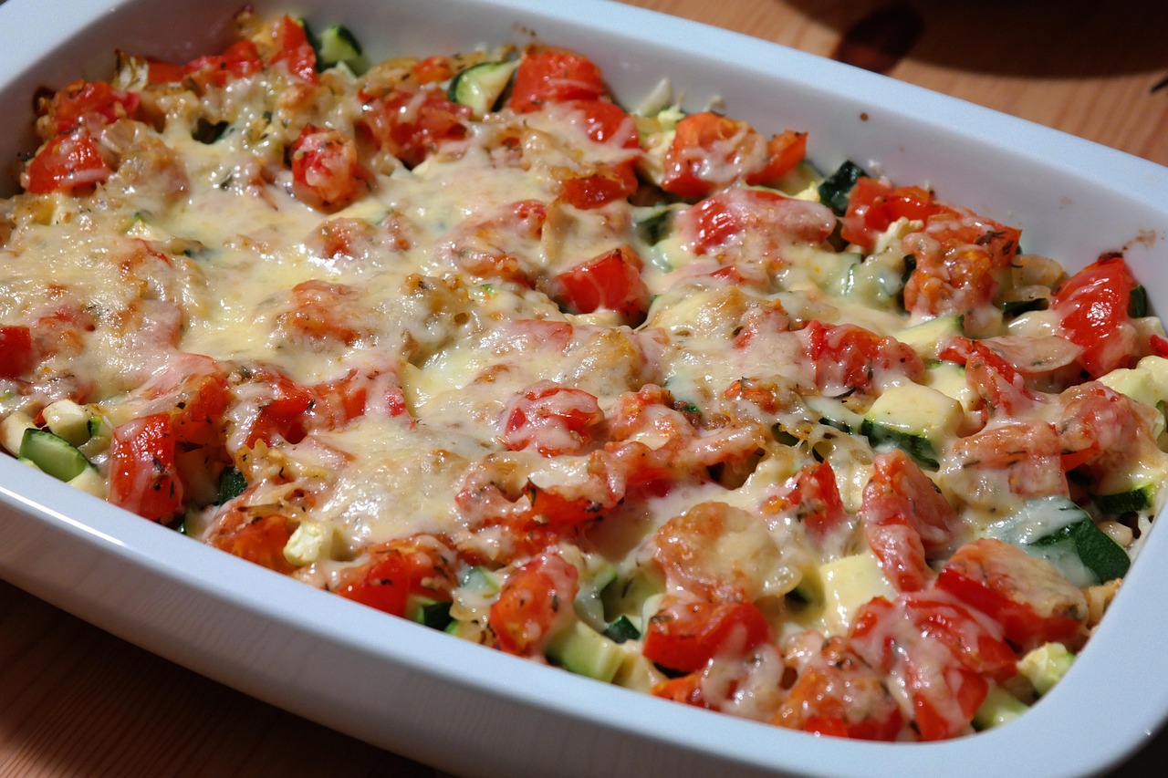 Zucchini and tomato gratin with melted cheese in a white baking dish