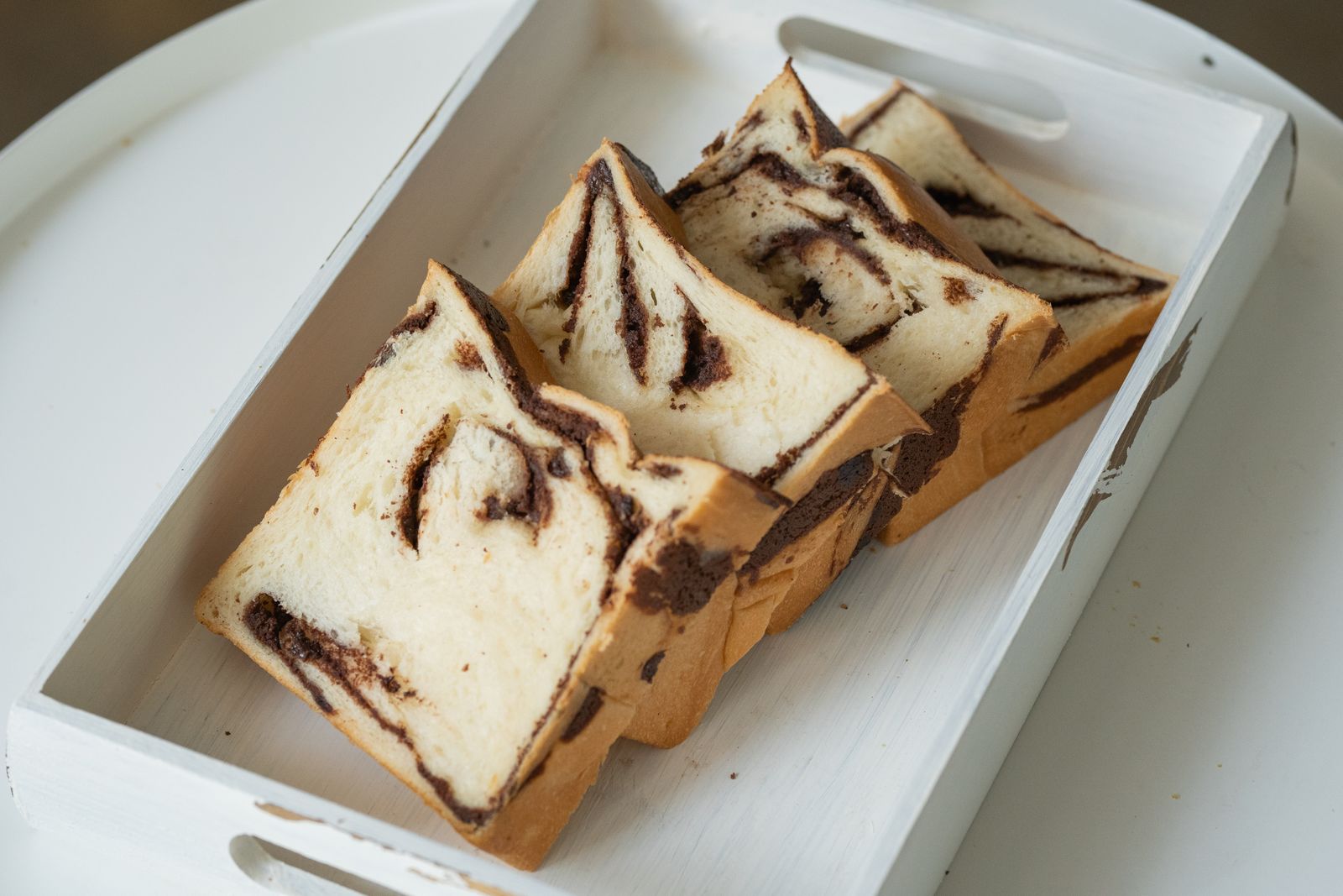 Slices of chocolate swirl bread in a white tray, ready to wrap