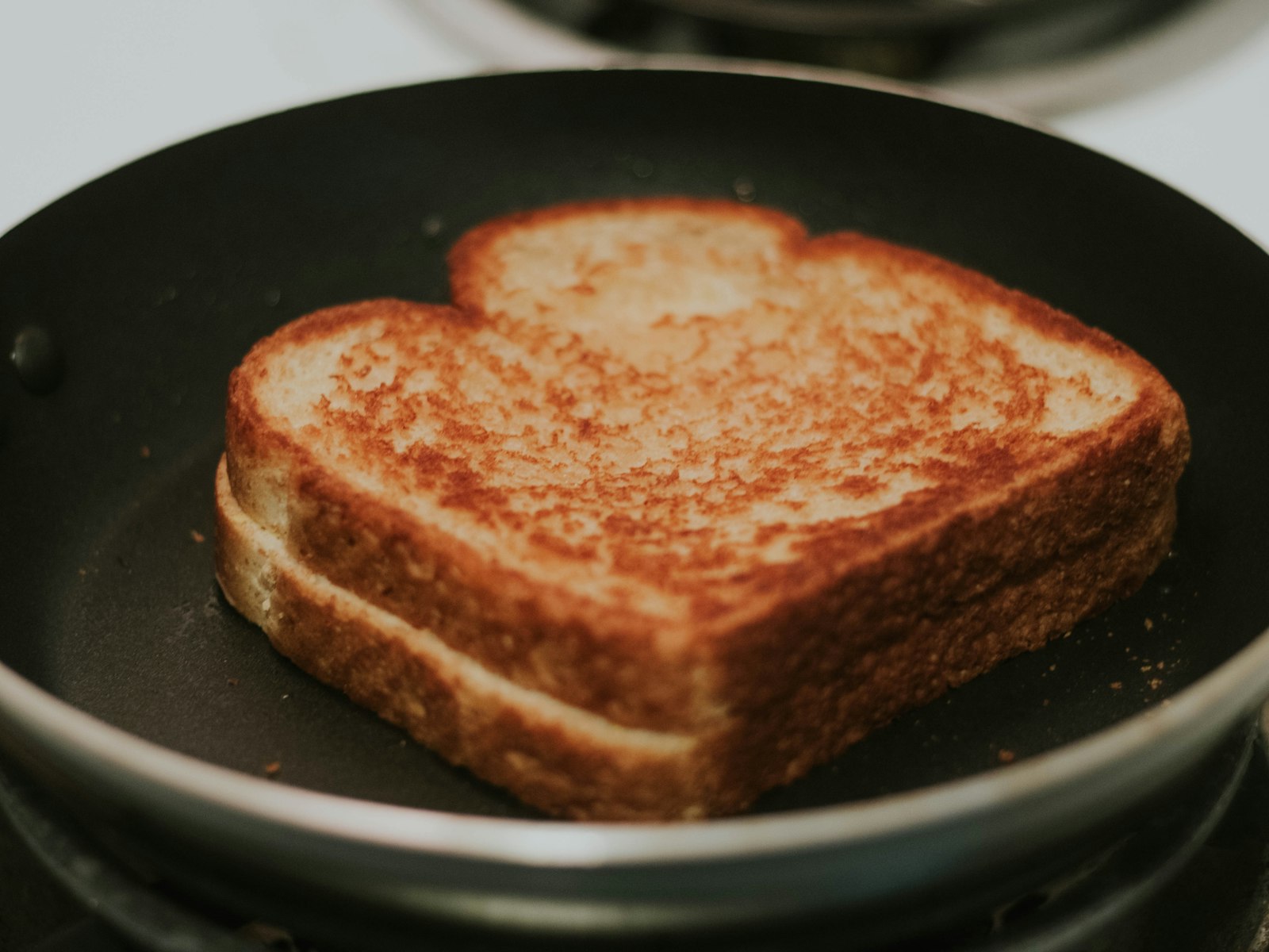 Golden grilled cheese sandwich toasting in a frying pan, a classic butter vs oil question