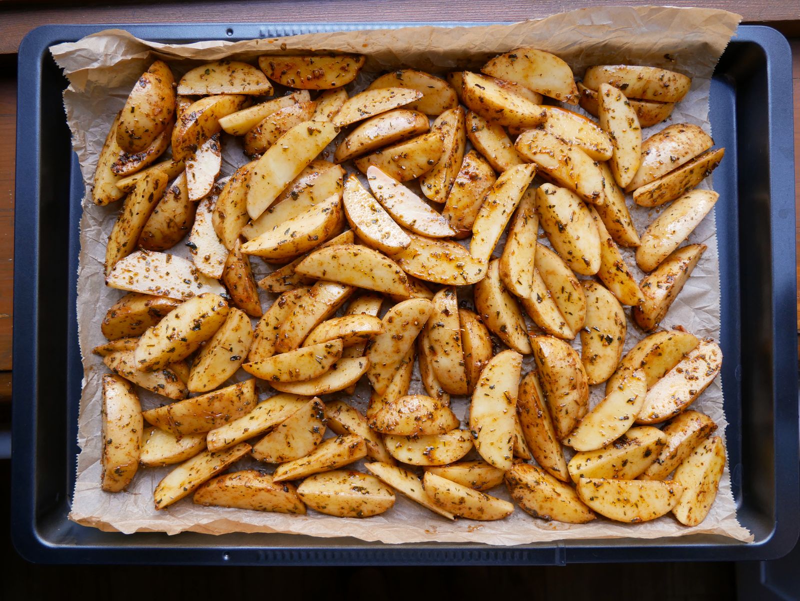 Crispy roasted potato wedges with herbs on a baking tray, a butter vs oil test