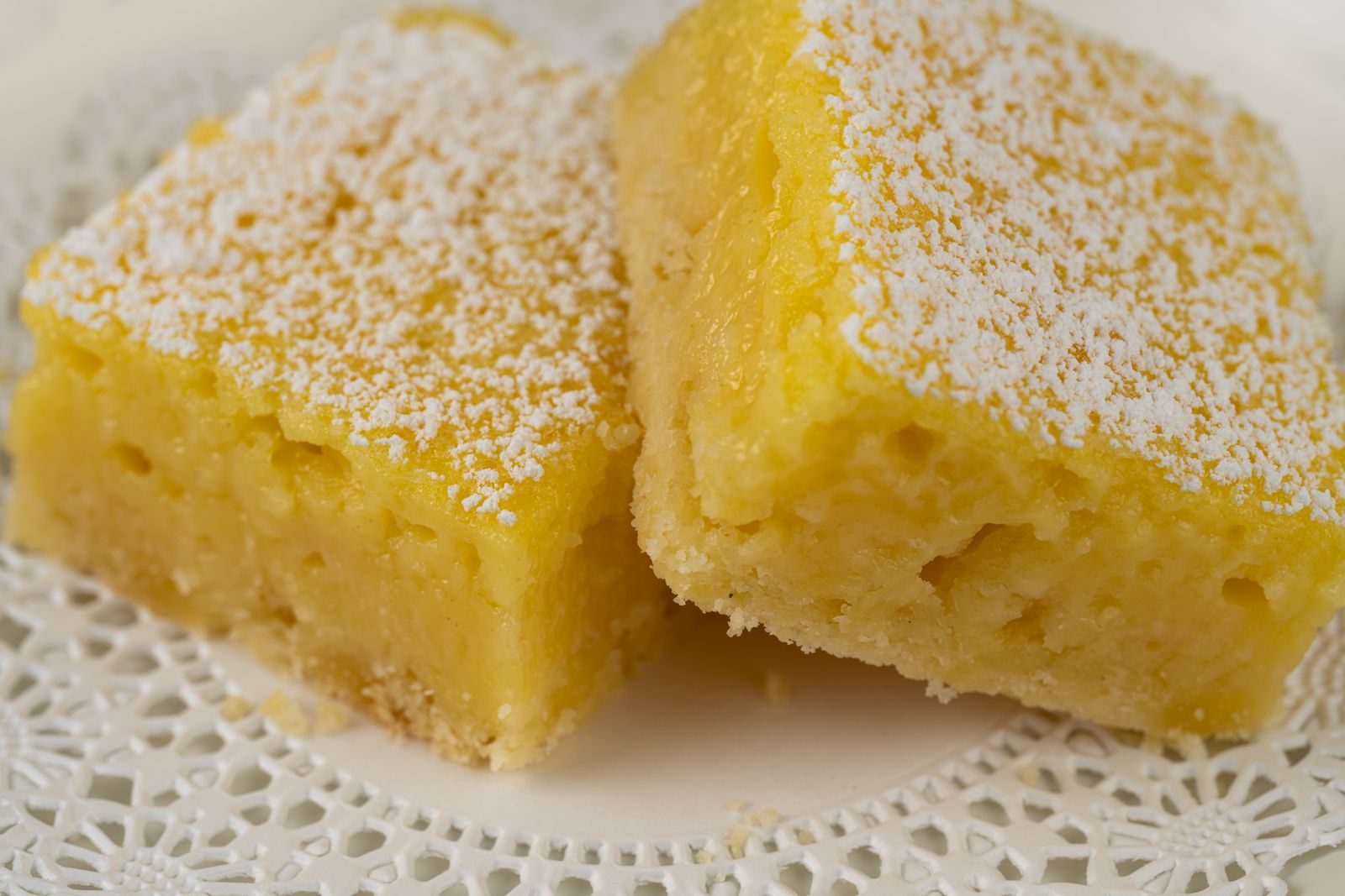 Two golden chess bars dusted with sugar on a lace doily
