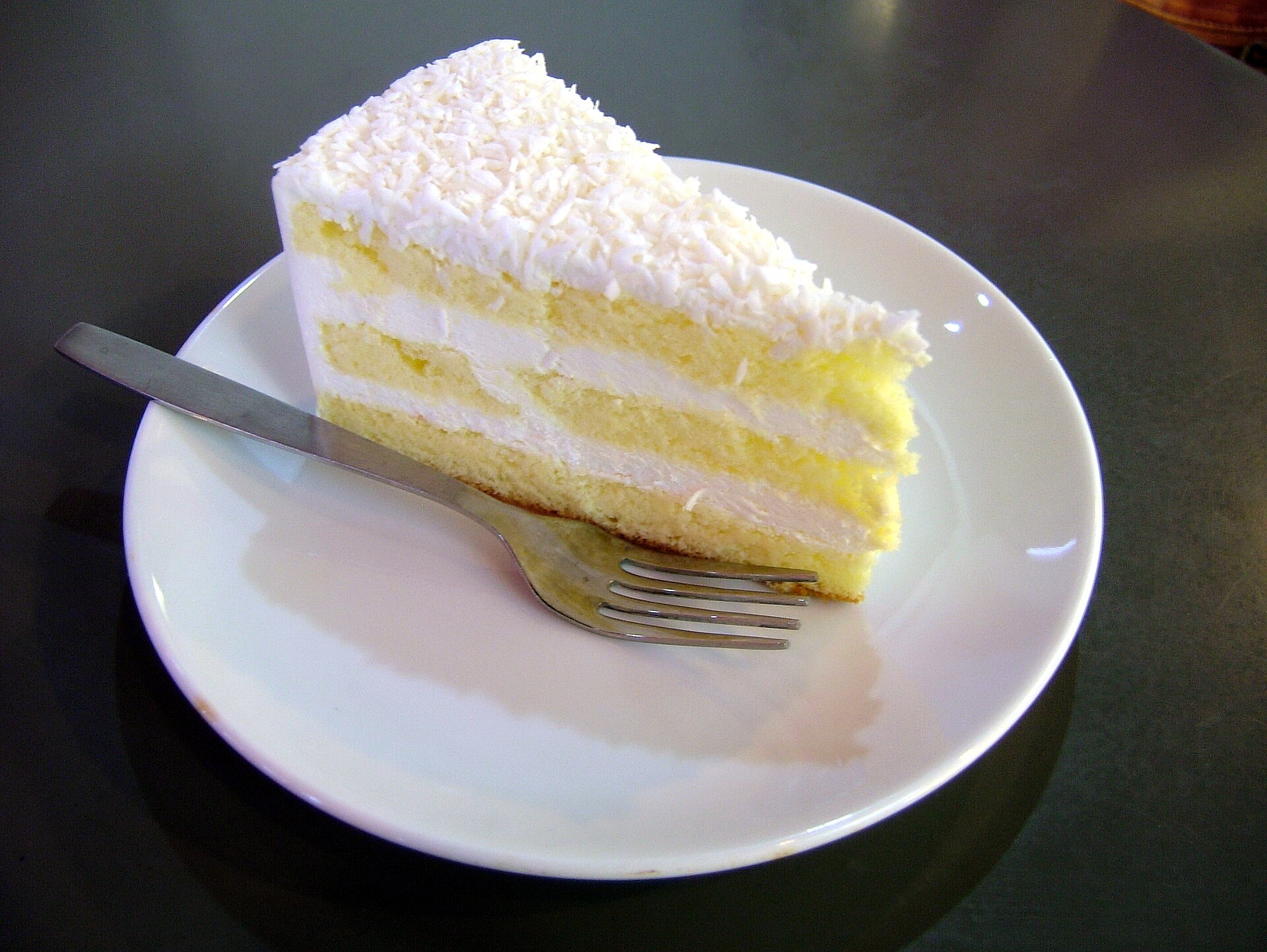 Slice of white coconut layer cake on a plate