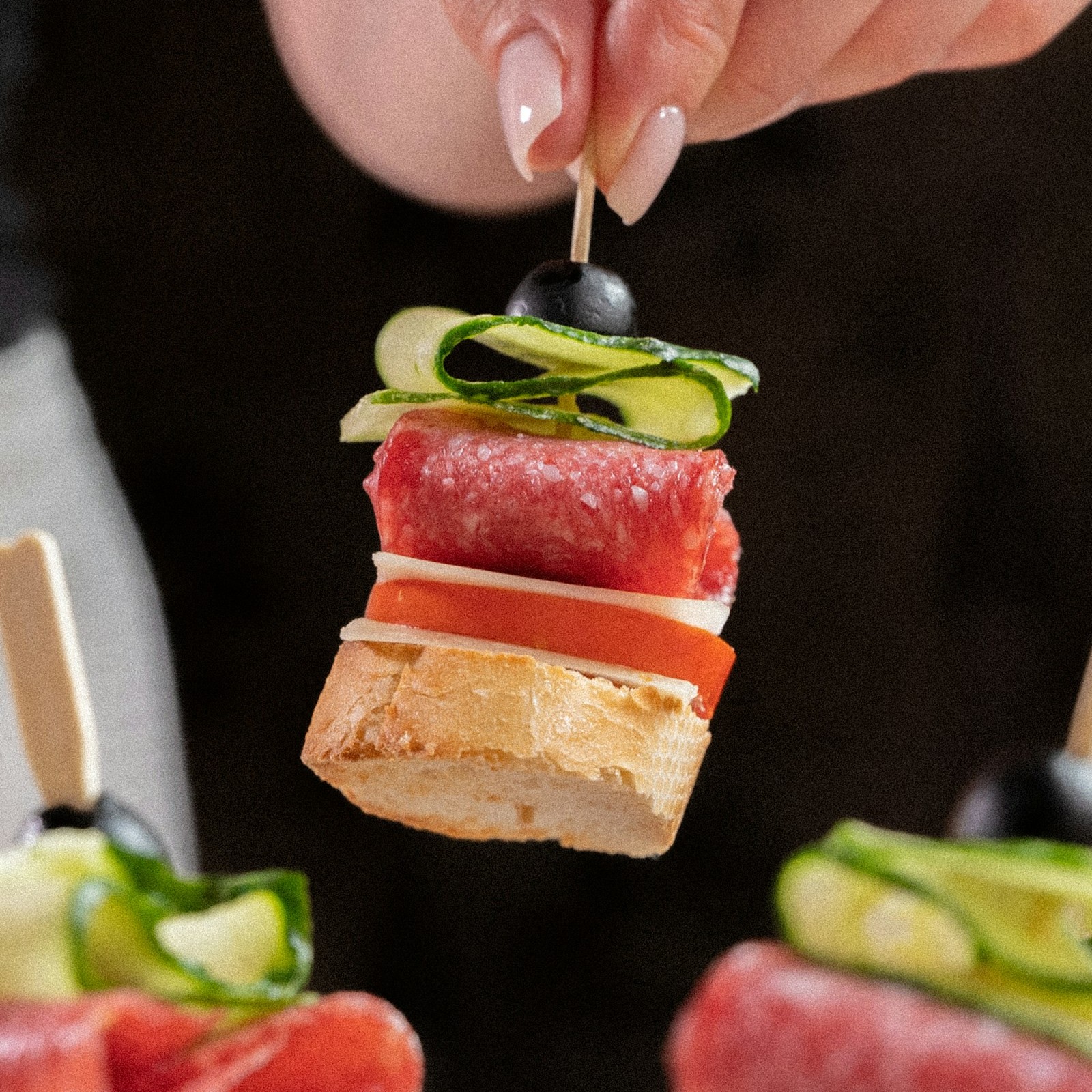 Stacked party skewer with bread, salami, mozzarella, cucumber and olive