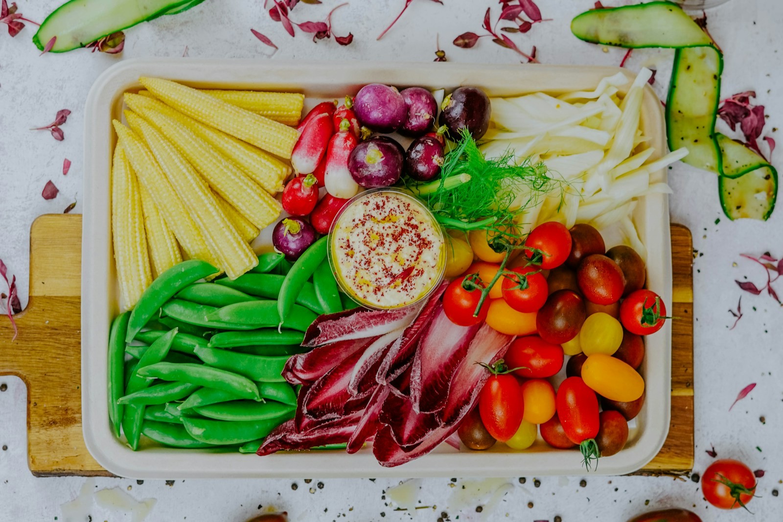 Rainbow vegetable board with a bowl of hummus