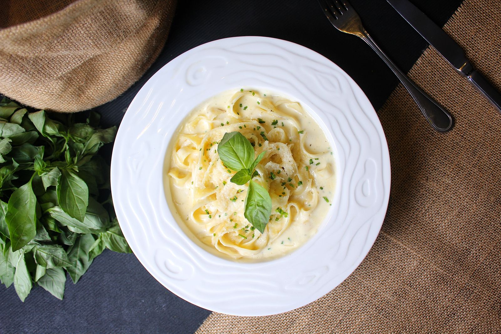 Creamy fettuccine Alfredo with fresh basil in a white bowl