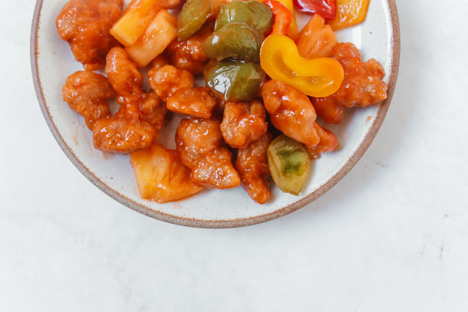 Sweet and sour pineapple chicken with peppers on a white plate