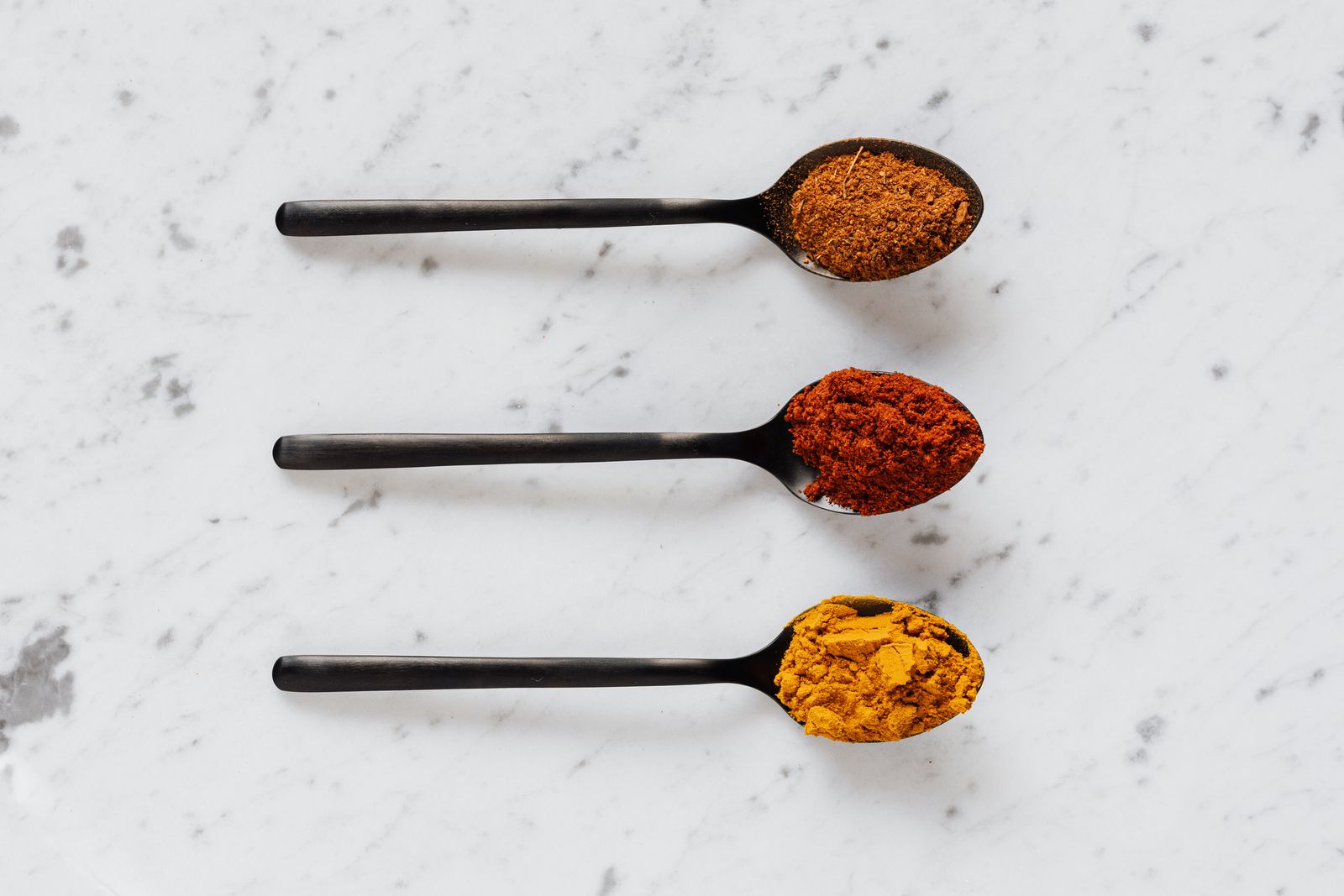 Spoons of paprika, cayenne and other ground spices for a homemade Creole seasoning