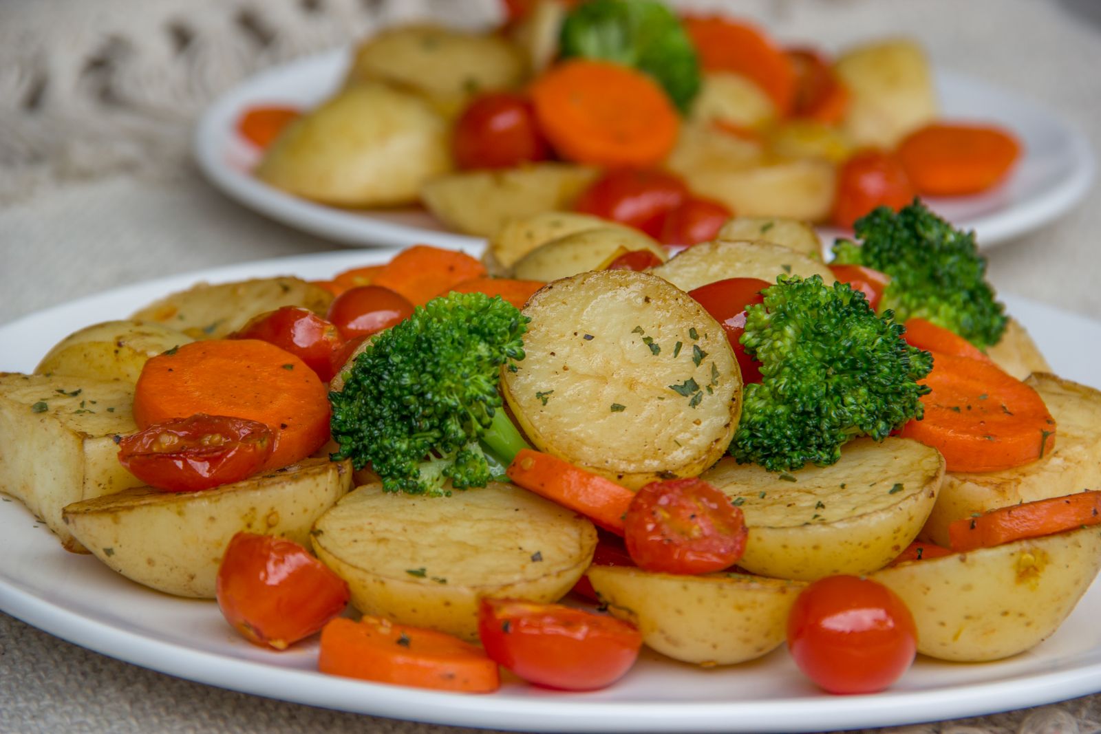 Plate of roasted potatoes, carrots, broccoli and tomatoes