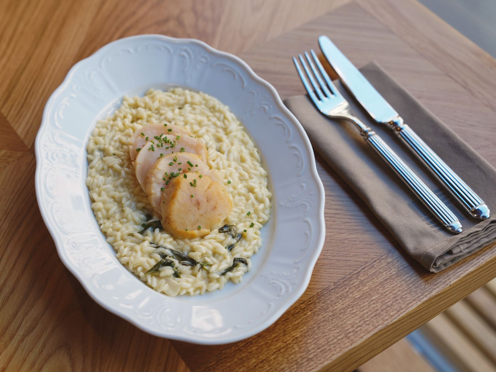 Creamy risotto on a white plate with a fork and knife