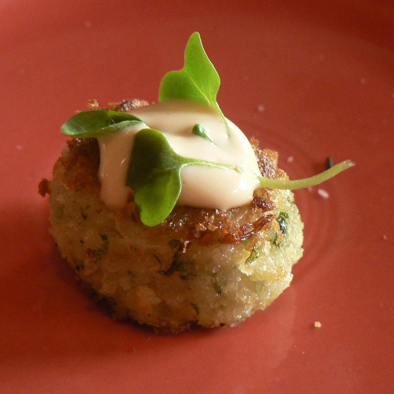 Mini crab cake topped with aioli and fresh greens