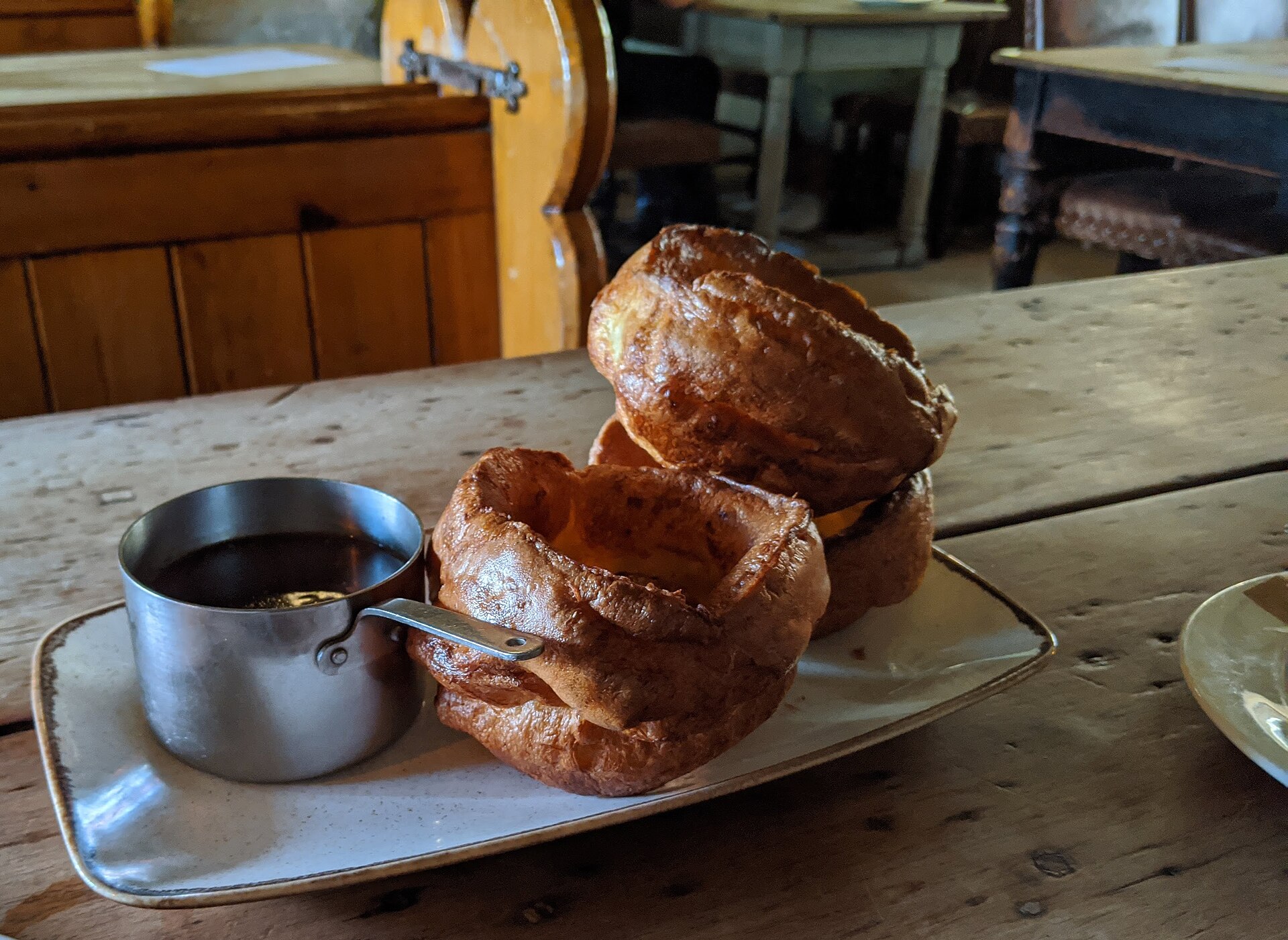 Tall golden Yorkshire puddings with a jug of gravy