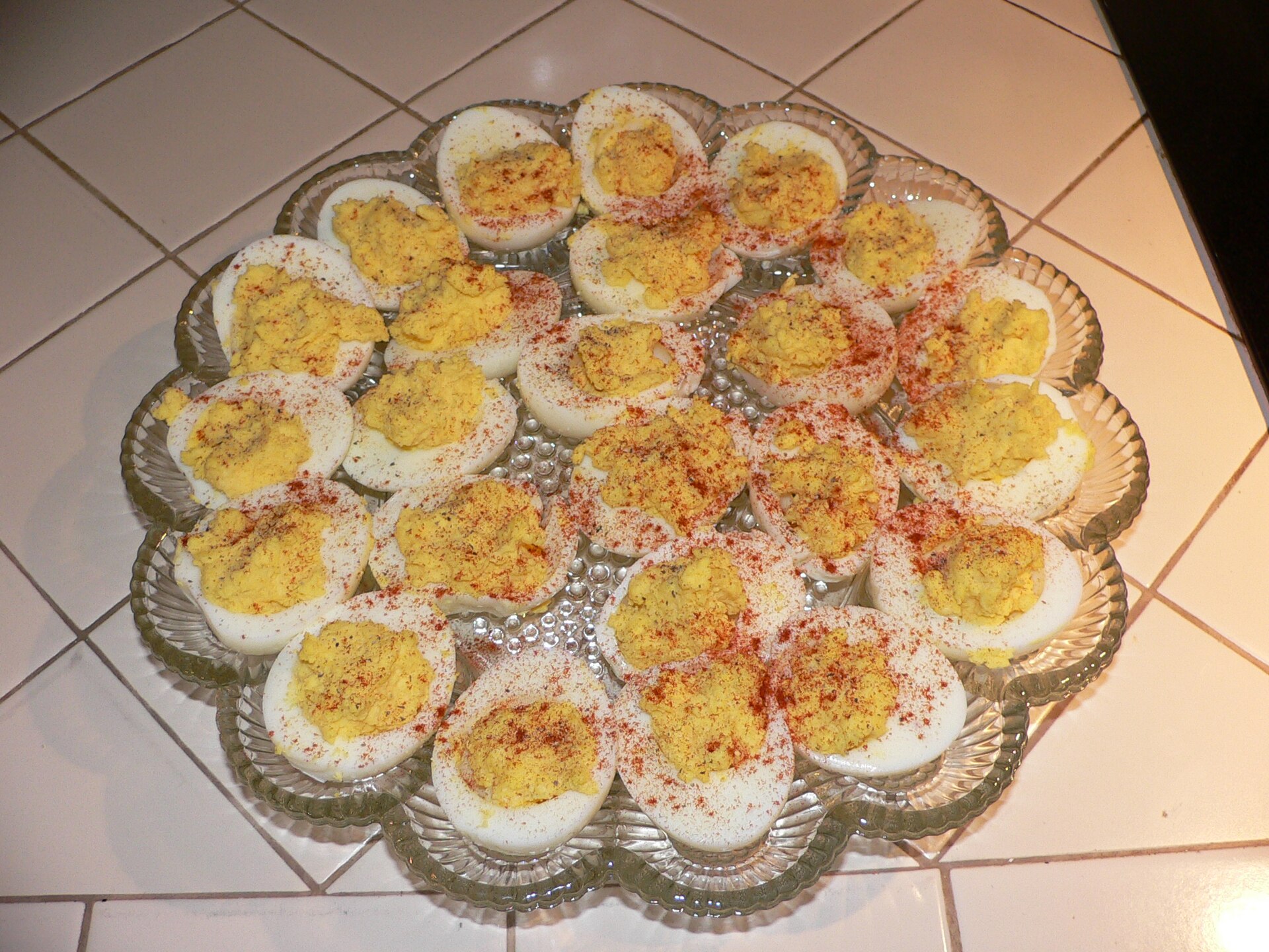 Glass platter of deviled eggs sprinkled with paprika