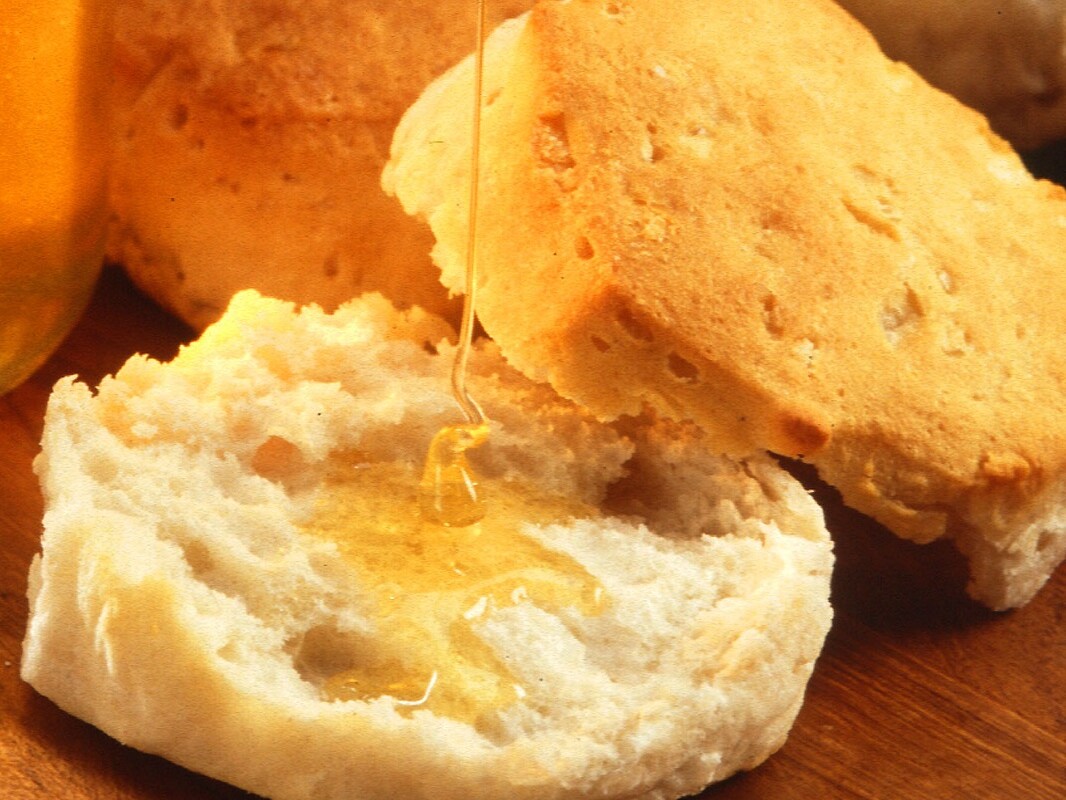 Warm buttermilk biscuit broken open with butter and honey