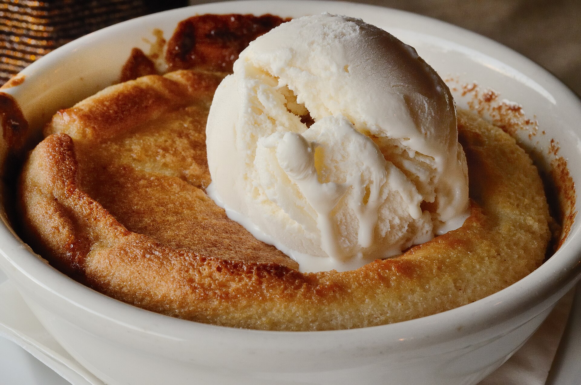 Warm peach cobbler topped with a scoop of vanilla ice cream