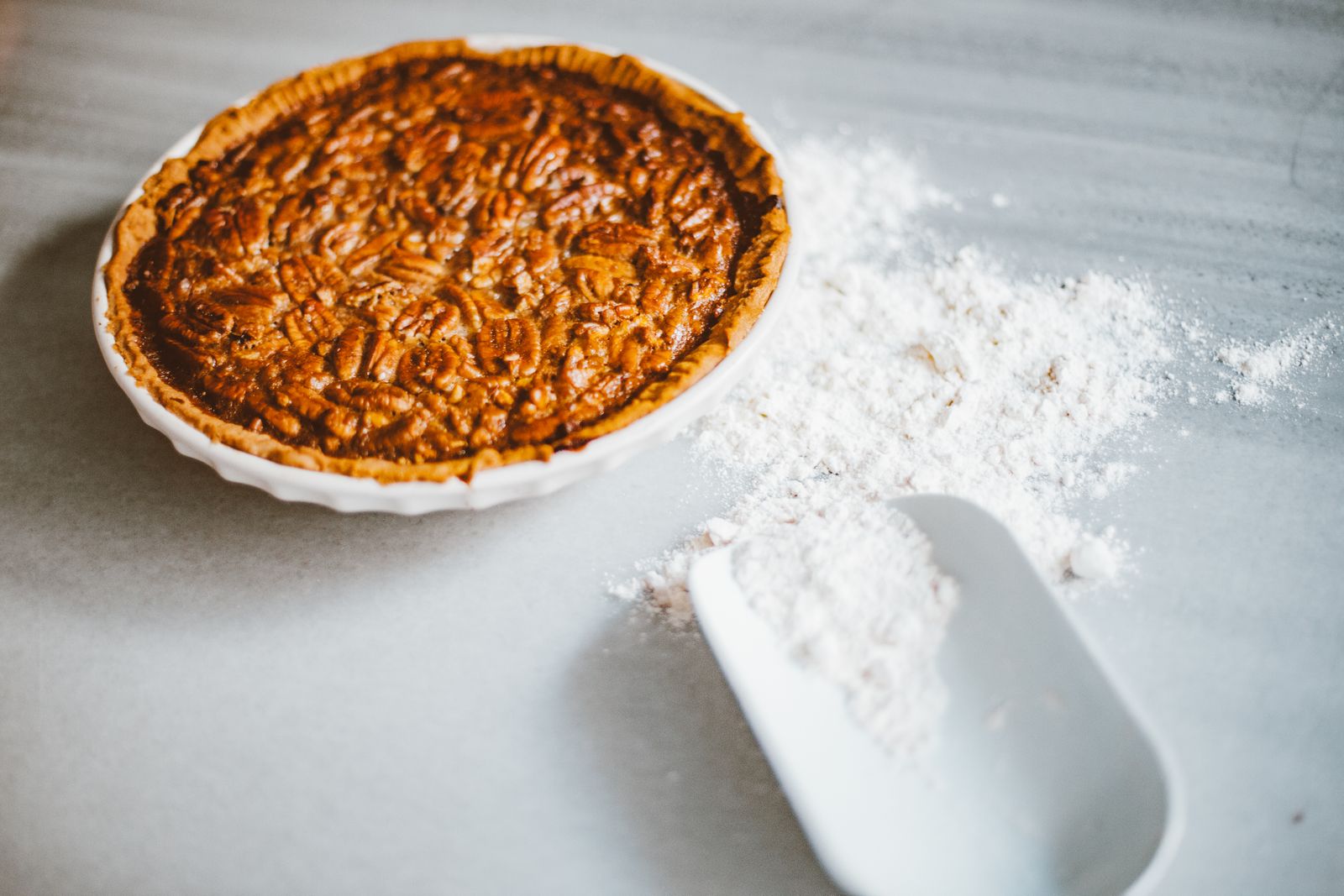 Whole pecan pie on a white table, the state pie behind many Texas Thanksgiving recipes