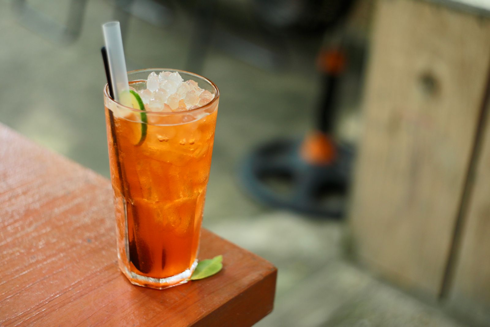 Tall glass of iced sweet tea with lime on a wooden table