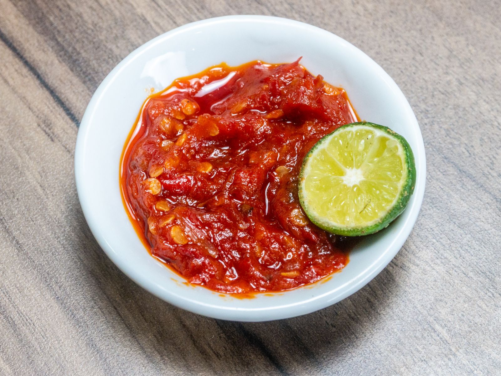 Bowl of fresh red chili sauce with lime for red beans and rice