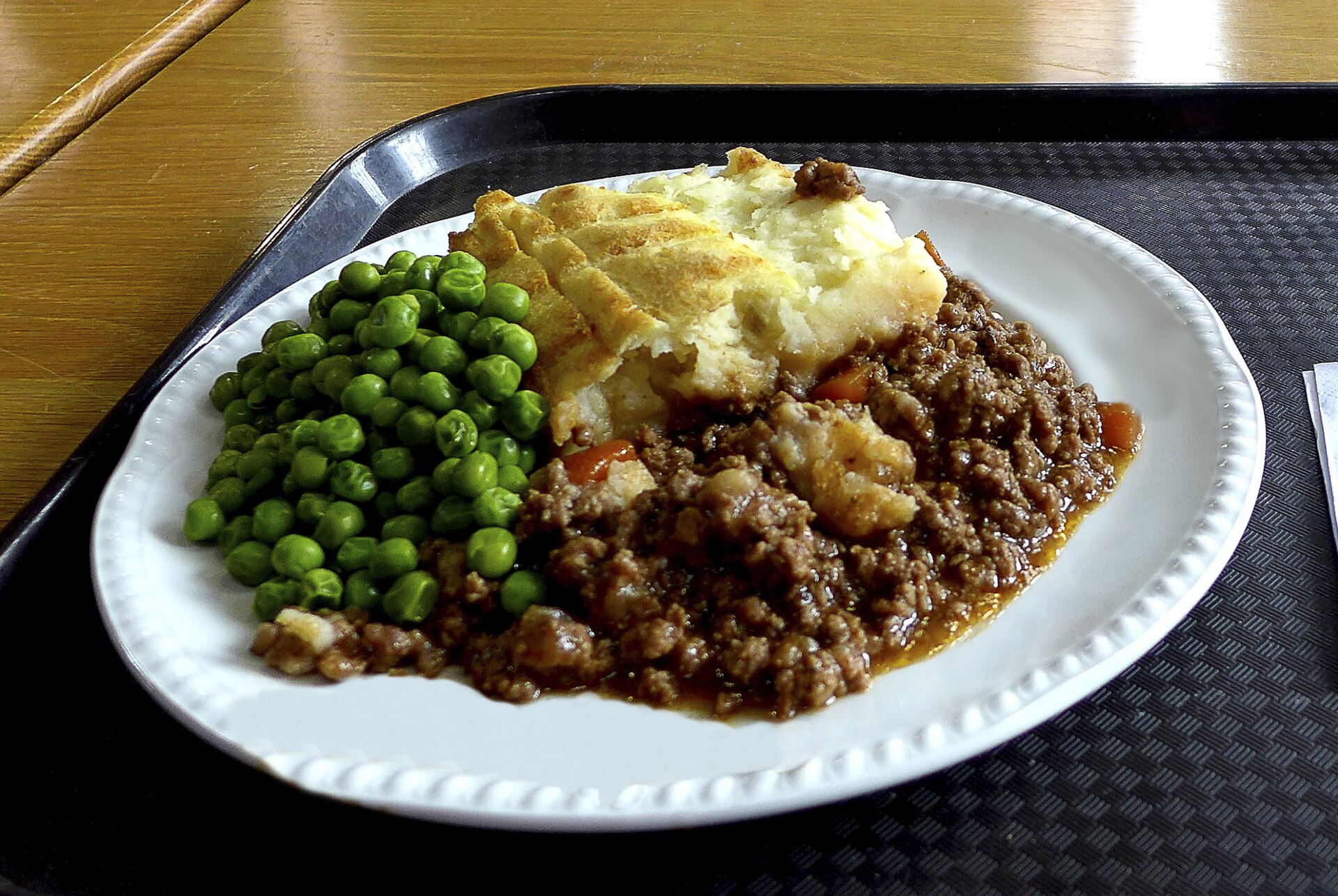 Plate of minced lamb under mashed potatoes with buttered green peas